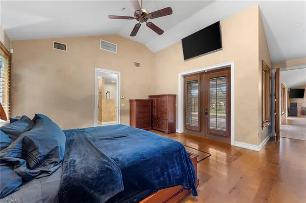 a spacious bedroom with a bed a flat screen tv and hallway
