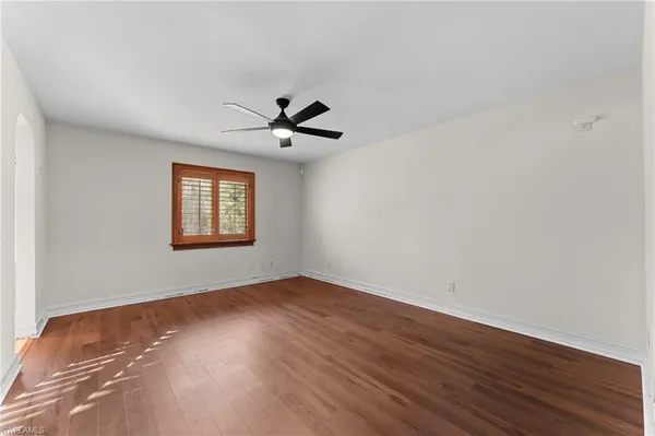 a view of an empty room with a window and wooden floor