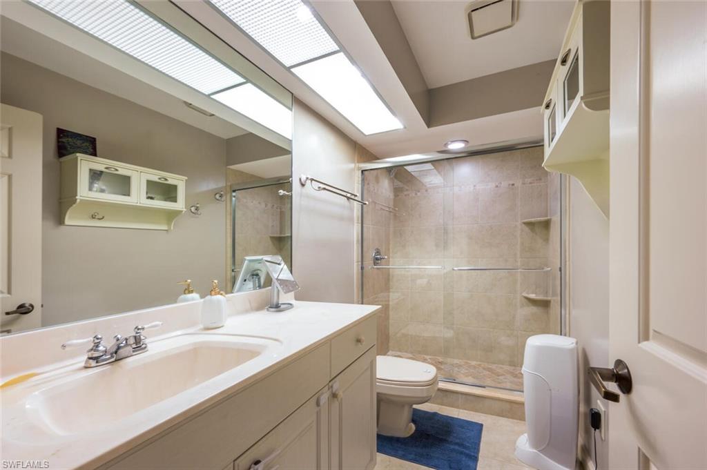 646 Augusta Boulevard Naples, FL 34113 - Photo 12 of 23 a bathroom with a granite countertop sink toilet a large mirror and shower