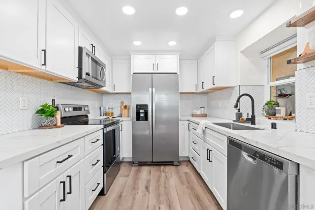 a kitchen with white cabinets stainless steel appliances and a counter space