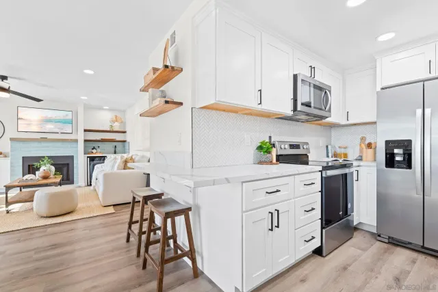 a kitchen with stainless steel appliances granite countertop a refrigerator a stove top oven a dining table and chairs with wooden floor