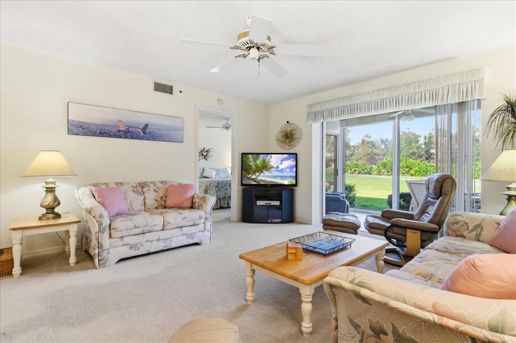 6713 Stone River Road, Unit 103 Bradenton, FL 34203 - Photo 14 of 86 a living room with furniture a large window and a flat screen tv