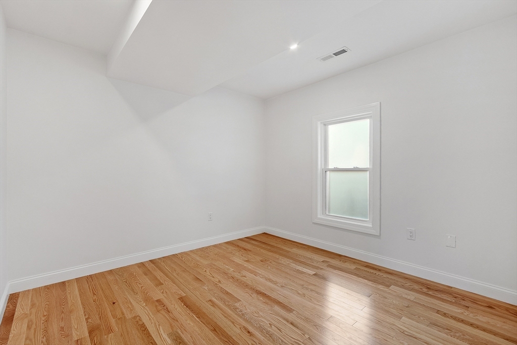 55 Mansfield Street, Unit A Gloucester, MA 01930 - Photo 12 of 18 an empty room with wooden floor and windows