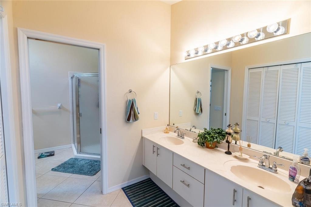 458 Countryside Drive Naples, FL 34104 - Photo 22 of 50 Full bath featuring double vanity, light tile patterned flooring, and a shower stall