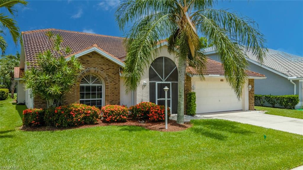 458 Countryside Drive Naples, FL 34104 - Photo 5 of 50 View of front of home with a tile roof, a front lawn, concrete driveway, a garage, and brick siding