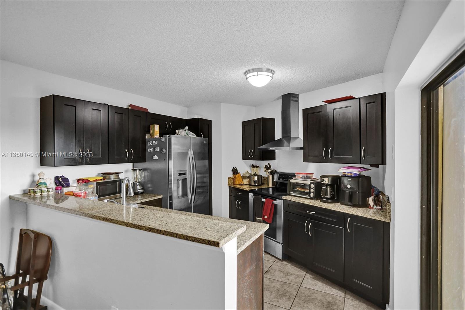 84 Springdale Circle Palm Springs, FL 33461 - Photo 11 of 32 a kitchen with stainless steel appliances a stove refrigerator and microwave