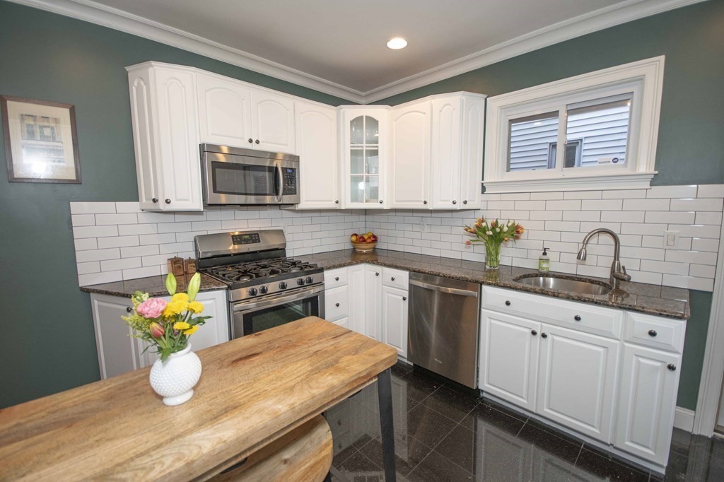 a kitchen with a sink dishwasher a stove a microwave oven a dining table and chairs