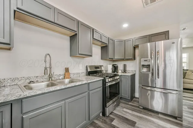a kitchen with stainless steel appliances granite countertop a refrigerator sink and stove
