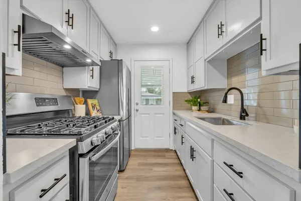 a kitchen with stainless steel appliances granite countertop a sink stove and cabinets