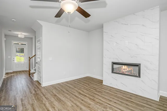 a view of an empty room with wooden floor and a ceiling fan