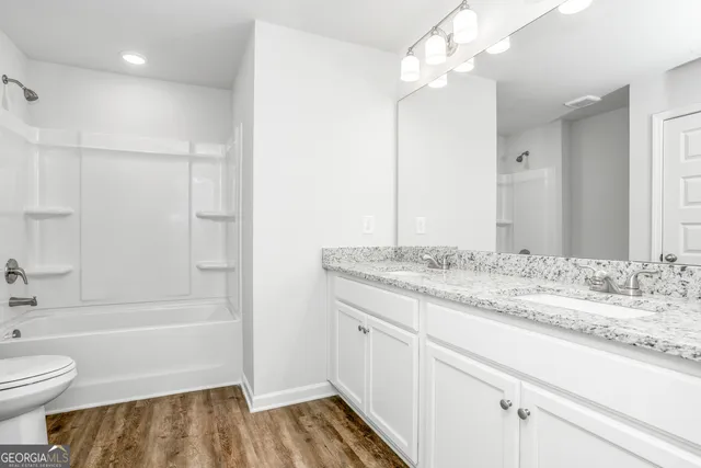 a bathroom with a granite countertop sink a toilet and shower