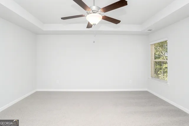 an empty room with a window and a ceiling fan