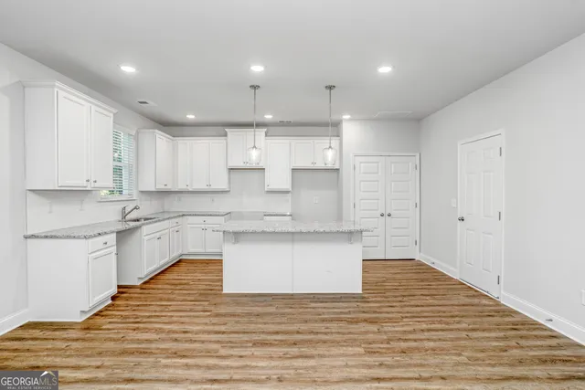 a large kitchen with granite countertop a white stove top oven and white cabinets