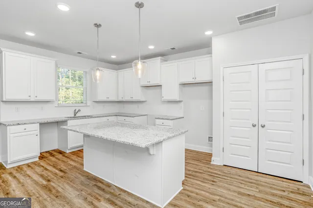 a kitchen with a sink dishwasher a stove a refrigerator and white cabinets with wooden floor