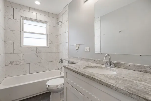 a bathroom with a granite countertop toilet a sink and a bathtub