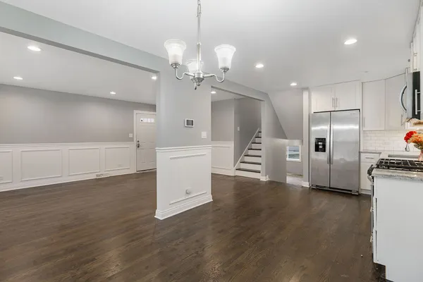 a large kitchen with stainless steel appliances a large counter top space wooden floor and a refrigerator