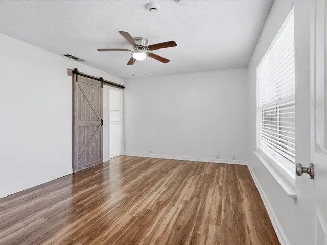 a view of empty room with wooden floor and fan