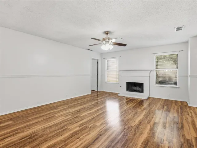 a view of empty room with wooden floor and fireplace