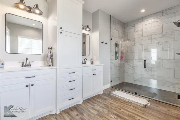 a bathroom with a double vanity sink mirror and shower