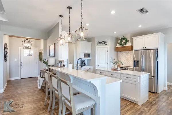 a large kitchen with kitchen island a chandelier and refrigerator