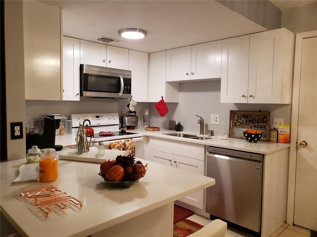 4876 Lake Ridge Road, Unit 5 Orlando, FL 32808 - Photo 2 of 11 a kitchen with a sink a stove and chairs