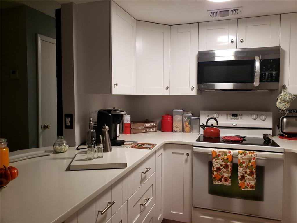 4876 Lake Ridge Road, Unit 5 Orlando, FL 32808 - Photo 3 of 11 a kitchen with stainless steel appliances granite countertop a sink and a stove