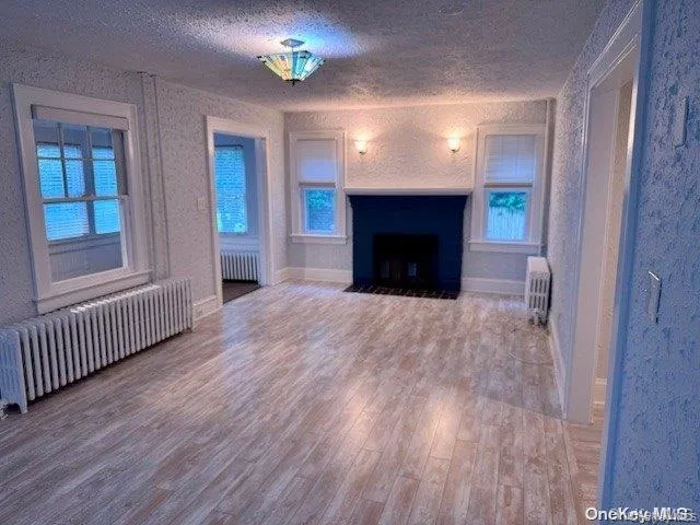 an empty room with wooden floor a fireplace and a window