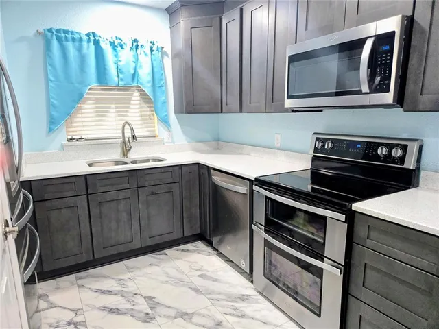 a kitchen with granite countertop a stove microwave and sink