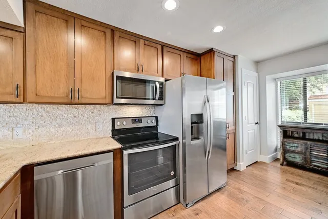 a kitchen with stainless steel appliances granite countertop a refrigerator stove and sink