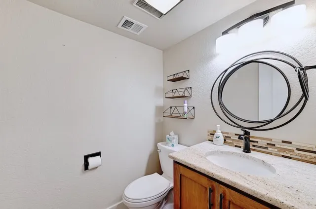 a bathroom with a granite countertop toilet a sink and a mirror