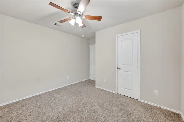 an empty room with a chandelier fan and windows