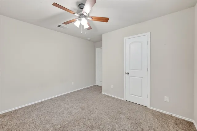 an empty room with a chandelier fan and windows