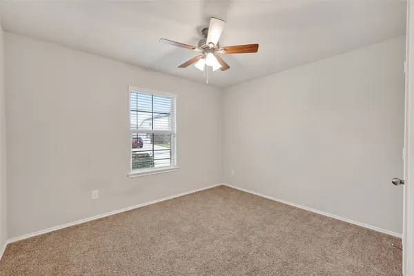 an empty room with a window and a fan