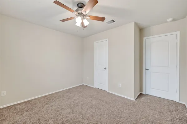 an empty room with a chandelier fan and windows