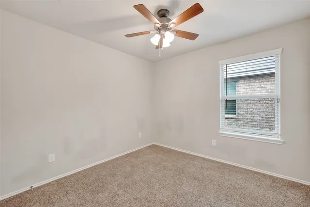 an empty room with a window and a fan