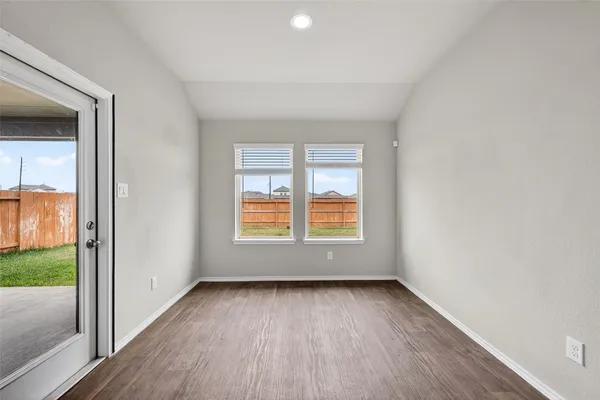 an empty room with kitchen view and a refrigerator
