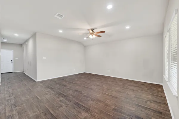 a view of an empty room with a window and wooden floor