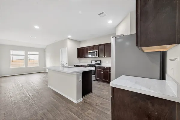 a kitchen with stainless steel appliances kitchen island a sink dishwasher a stove and a refrigerator