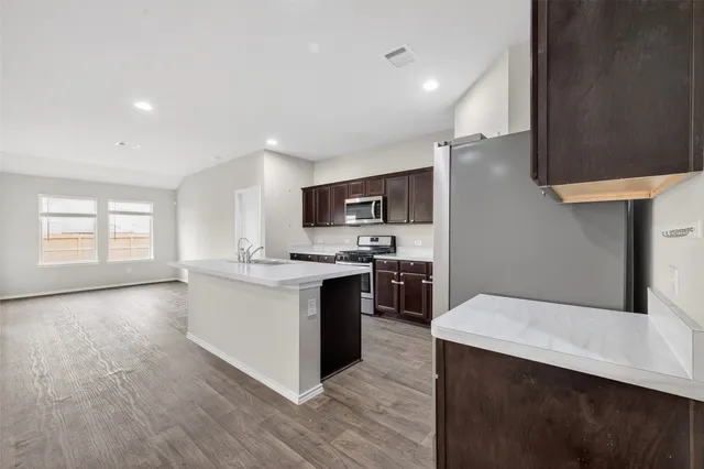 a kitchen with stainless steel appliances kitchen island a sink dishwasher a stove and a refrigerator