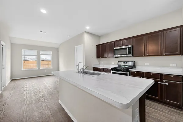 a kitchen with a stove a sink a microwave a refrigerator and cabinets