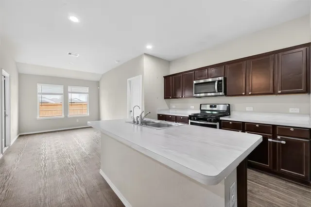 a kitchen with a stove a sink a microwave a refrigerator and cabinets