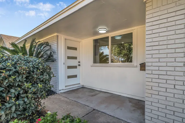 a view of a house with a yard and potted plants