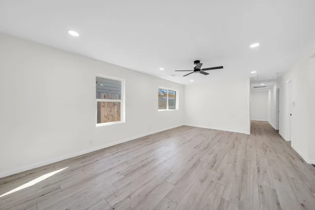 an empty room with wooden floor and windows