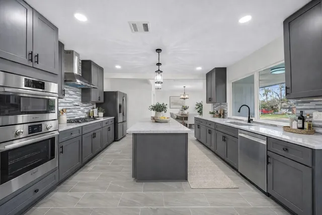 a large kitchen with stainless steel appliances kitchen island granite countertop a stove top oven a sink dishwasher and a refrigerator