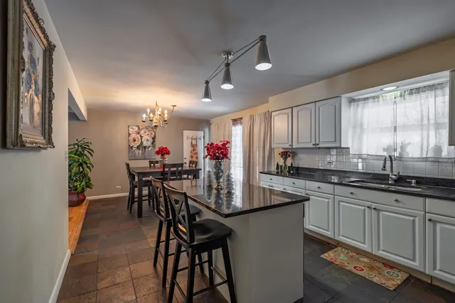 a kitchen with stainless steel appliances granite countertop table chairs sink and cabinets