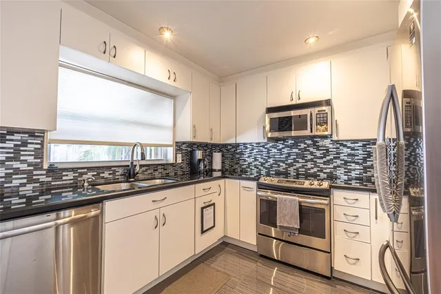 a kitchen with granite countertop a sink stainless steel appliances and cabinets
