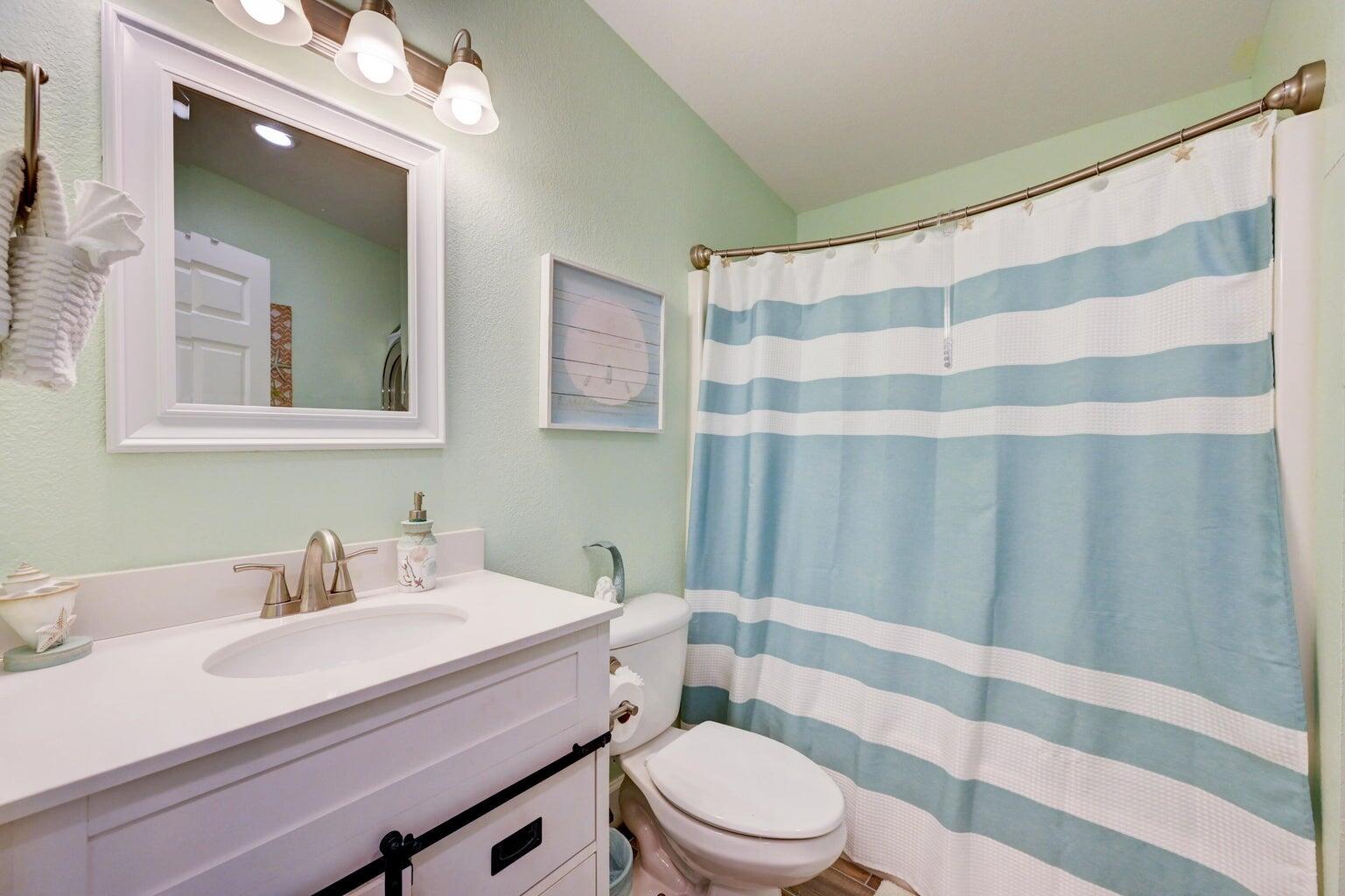 239 Lower Matecumbe Road, Unit 239 Key Largo, FL 33037 - Photo 28 of 69 a bathroom with a sink a toilet a mirror and shower curtain