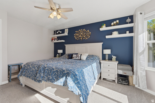 11189 Ohenry Road East Sandy, UT 84070 - Photo 15 of 44 Bedroom featuring a prominent accent wall, a multi-pane window, and a ceiling fan with integrated lighting