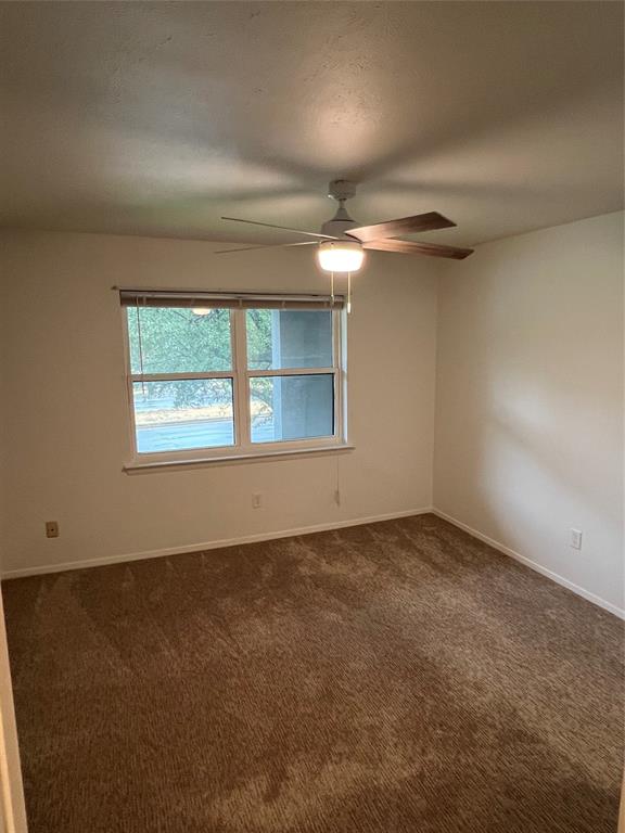 3929 Inwood Road, Unit 2021 Dallas, TX 75209 - Photo 12 of 24 Neutral wall paint with window, ceiling fan with light fixture, and brown carpet flooring