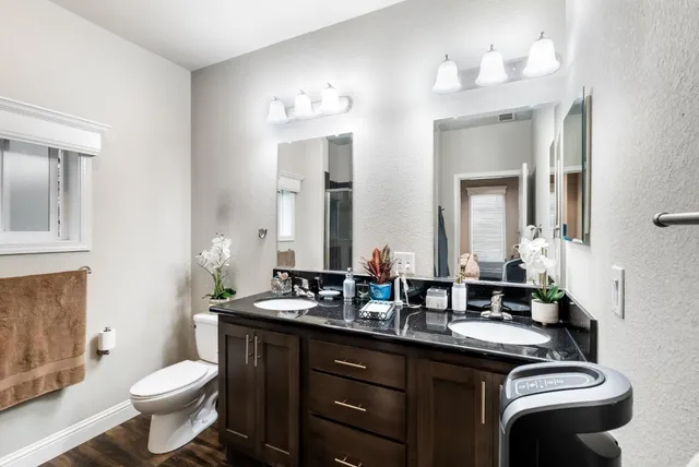 a bathroom with a double vanity sink toilet and mirror